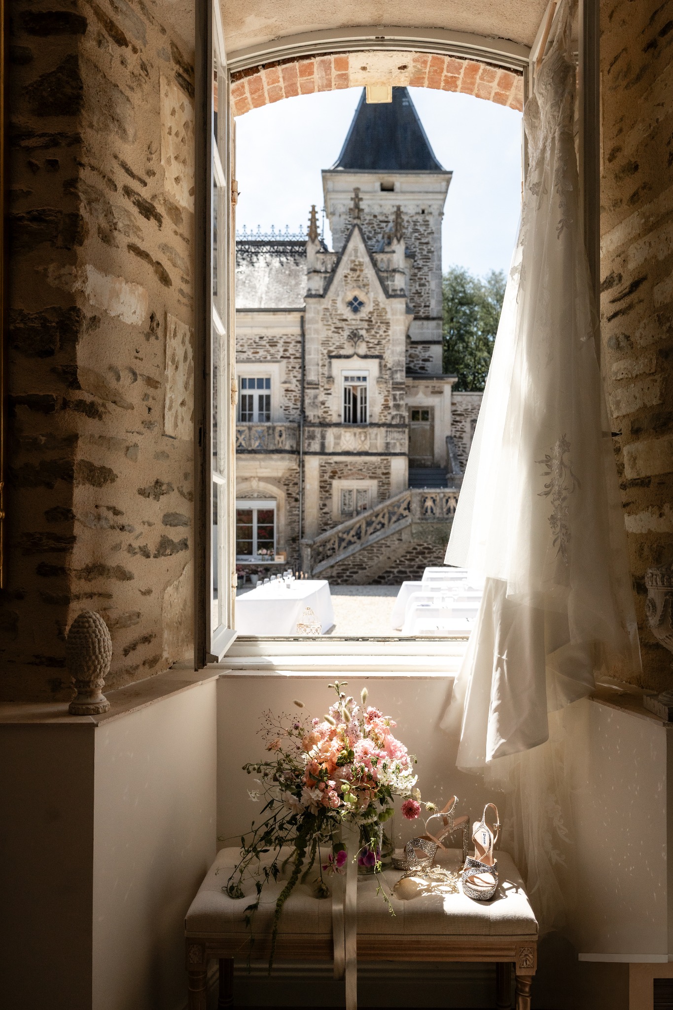 Wedding flowers and bridal details at a château window overlooking the courtyard