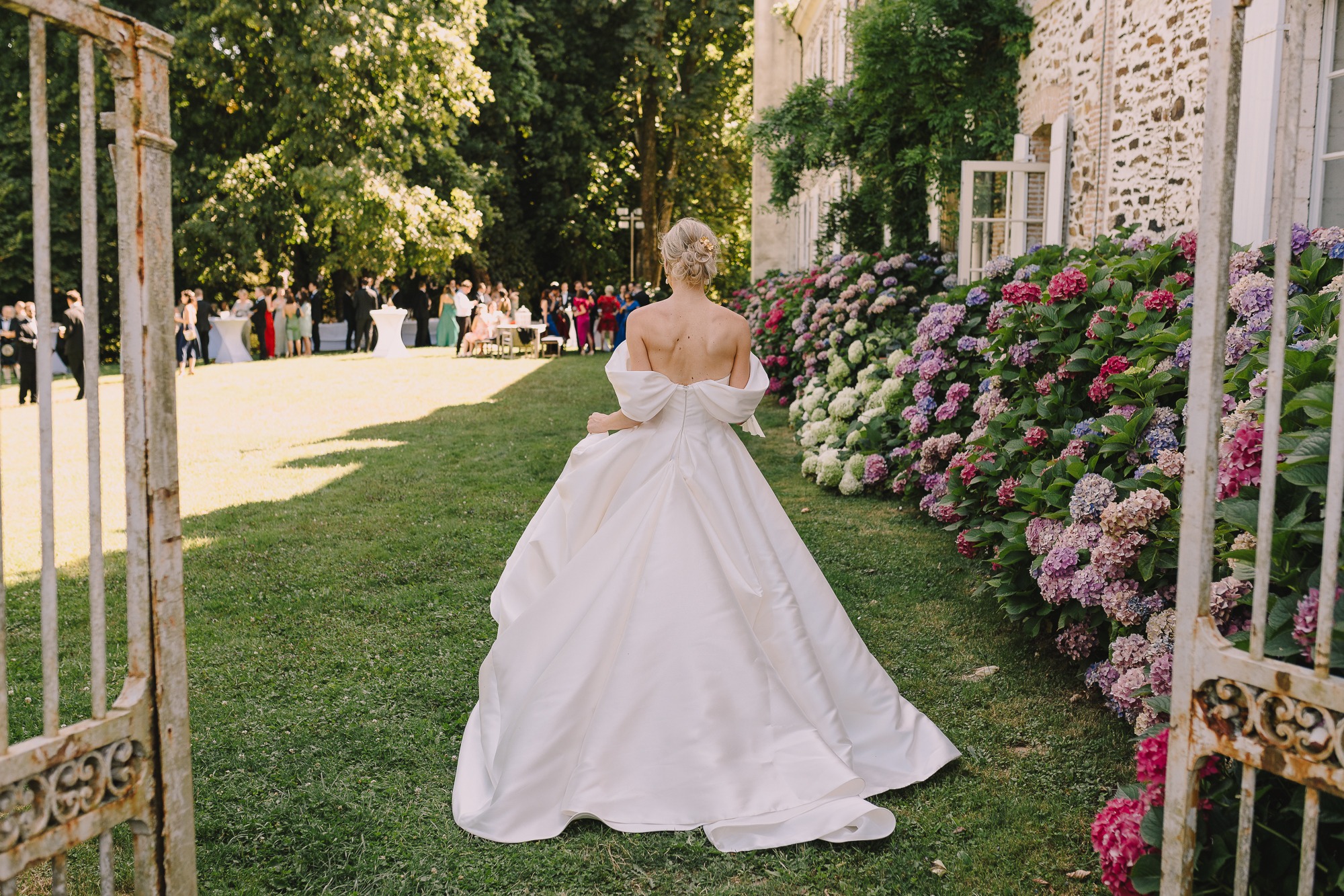 Bride entering through the château garden gates beside hydrangeas