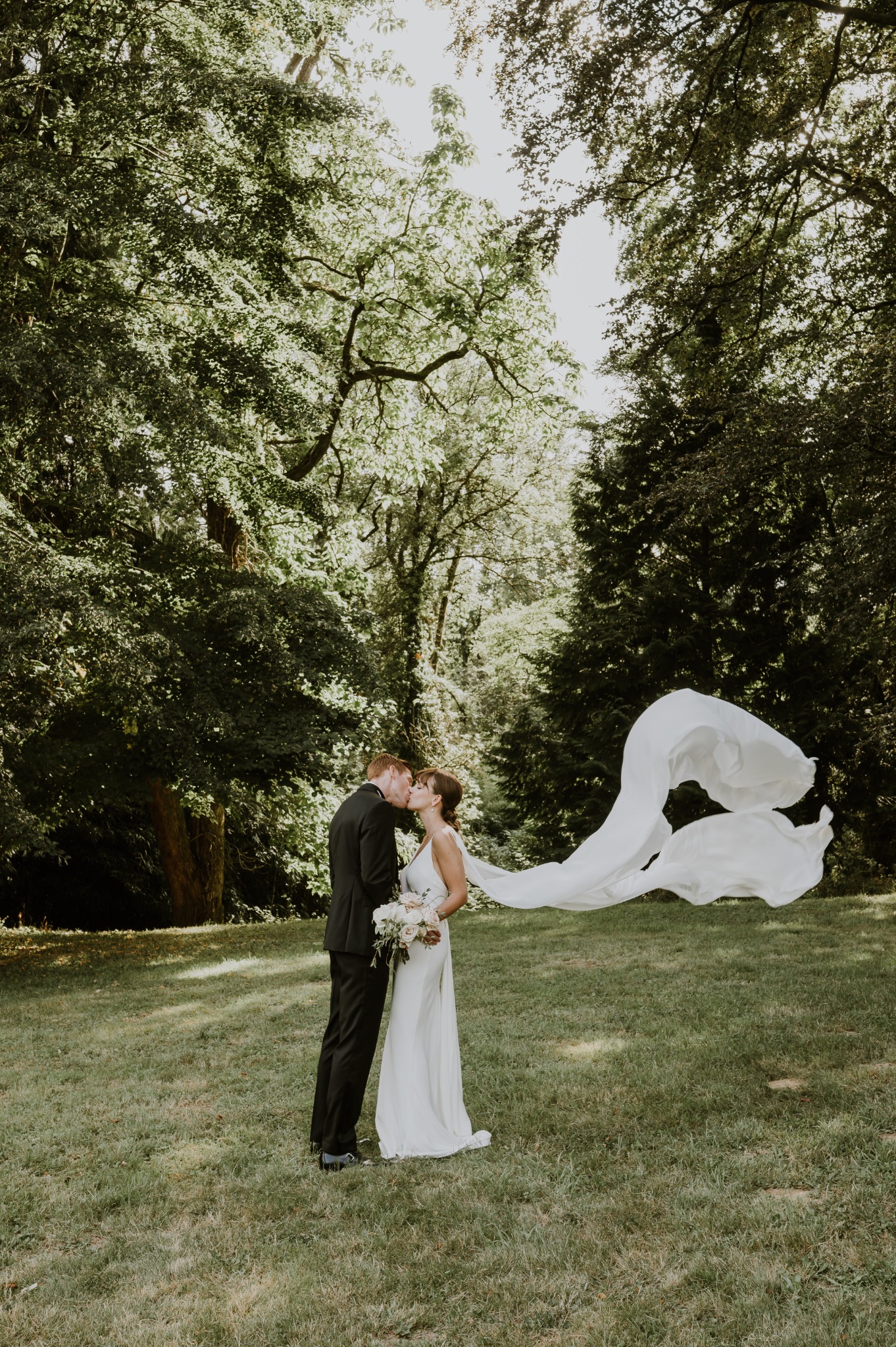 Veronika and Ronan beneath the trees, with the bride’s veil caught in the wind