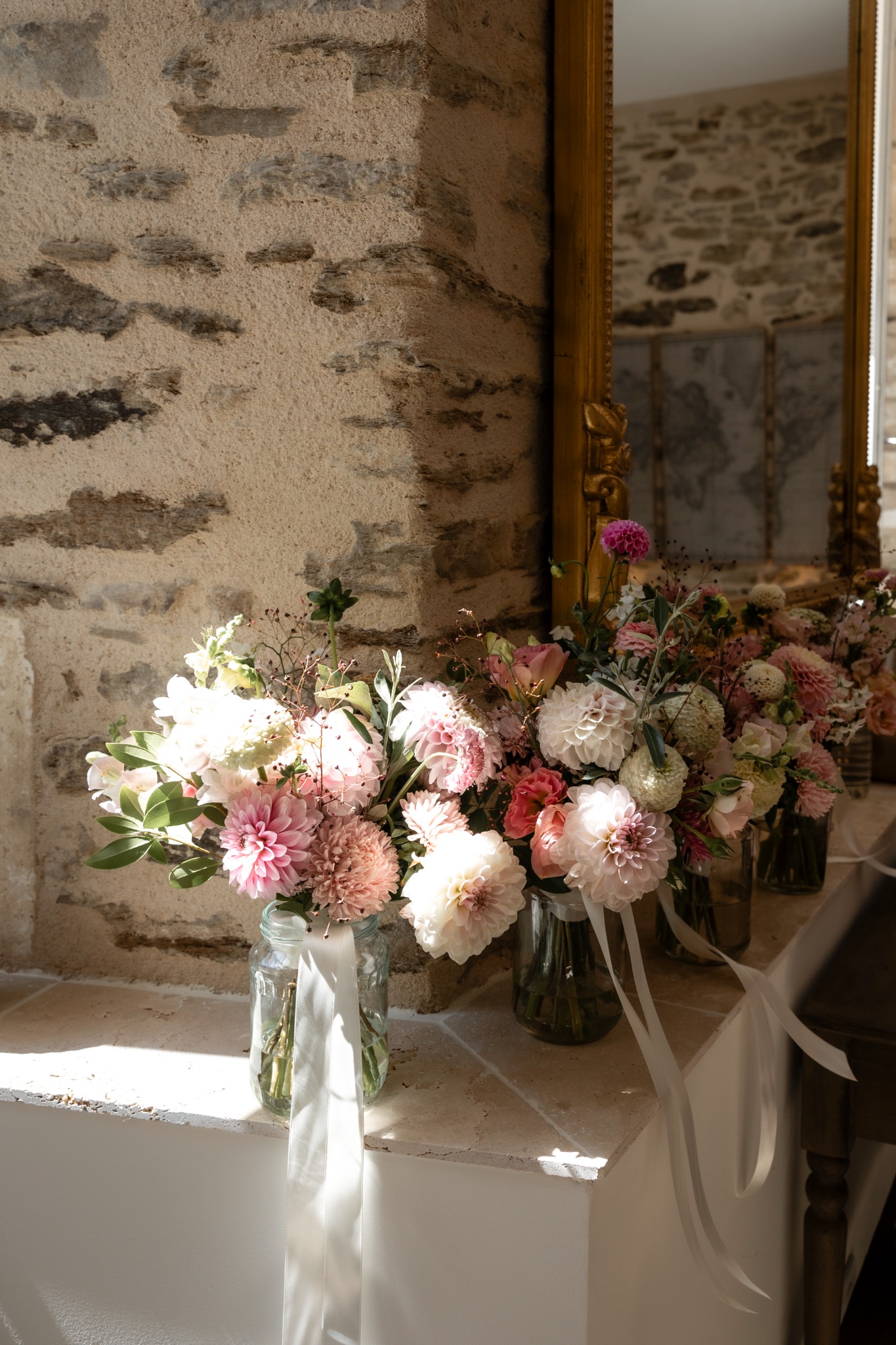 Wedding flowers arranged in a château room beside an antique mirror
