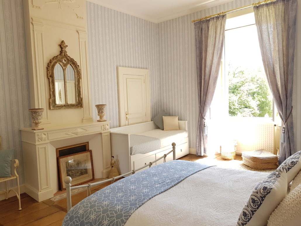 Blue and white bedroom with fireplace and balcony doors