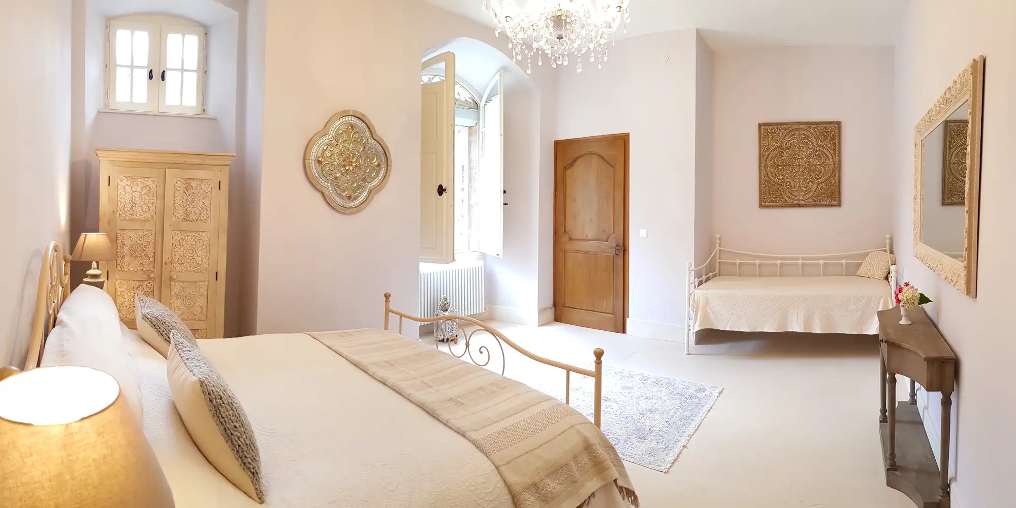 Softly lit château bedroom with a crystal chandelier and arched doorway