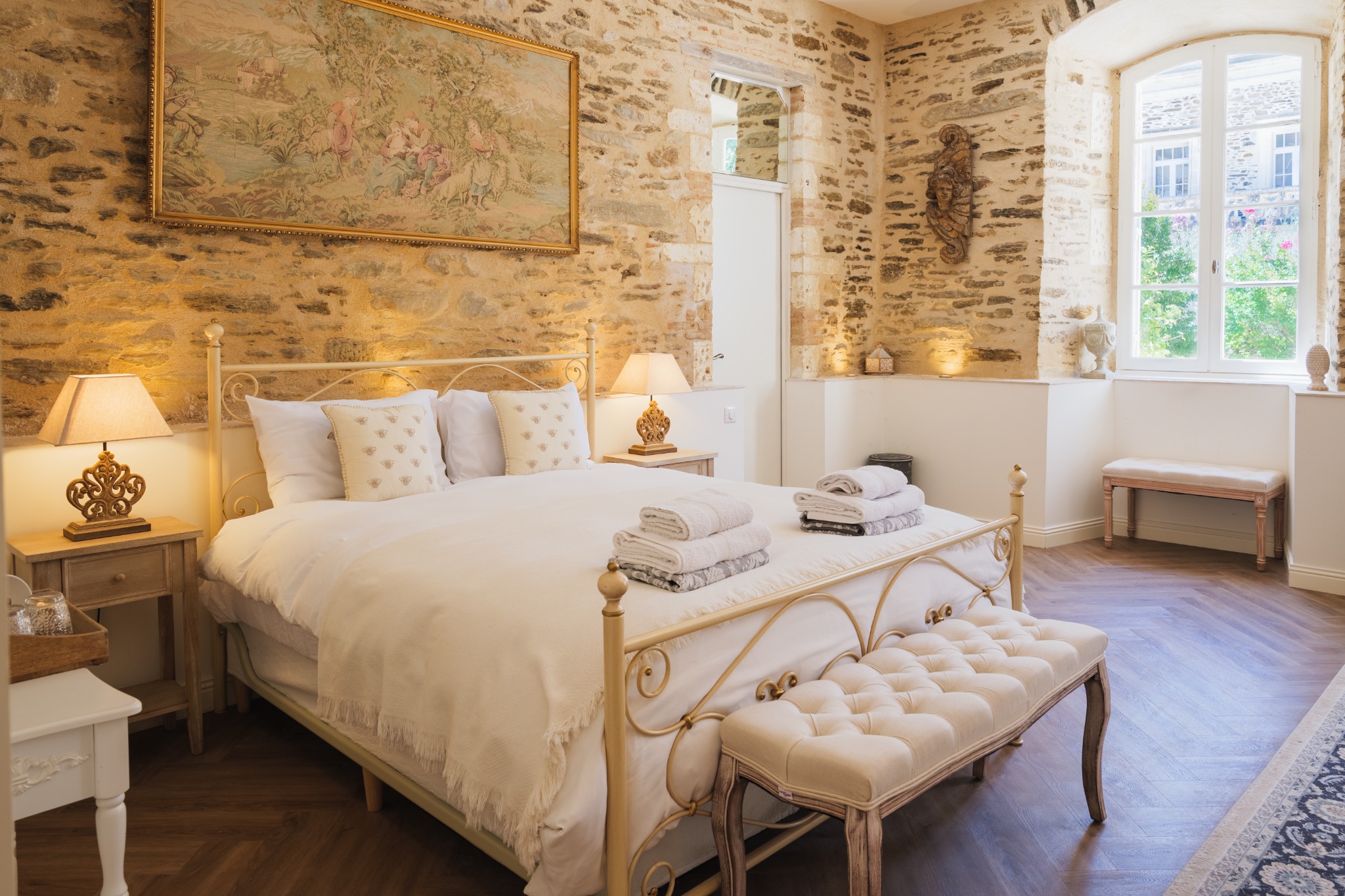 Five-star château bedroom with exposed stone, antique tapestry and window seat overlooking the courtyard